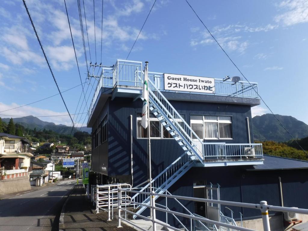 ein Gebäude mit einem Schild an der Seite in der Unterkunft Guest House Iwato in Takachiho