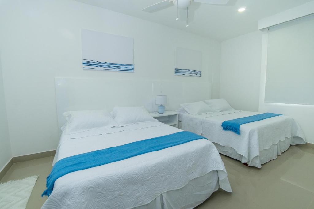 two beds in a room with white and blue sheets at Hermoso apartamento en la playa in Cartagena de Indias