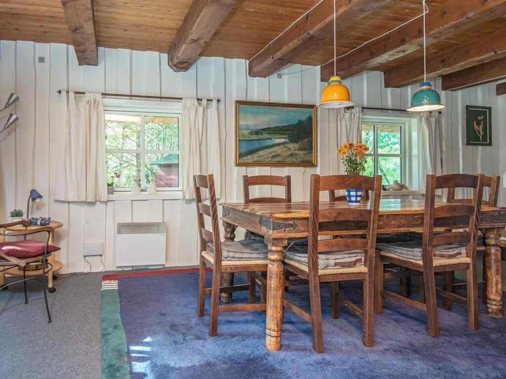 ein Esszimmer mit einem Holztisch und Stühlen in der Unterkunft 7 person holiday home in R m in Lakolk