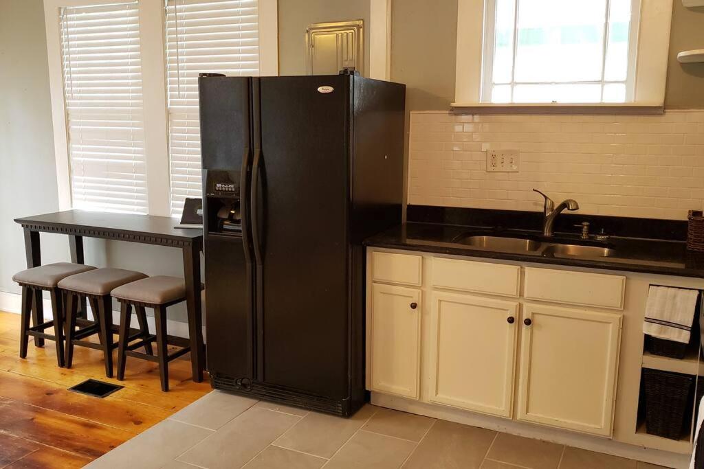 a kitchen with a black refrigerator and a table at The Lafayette House in Mobile