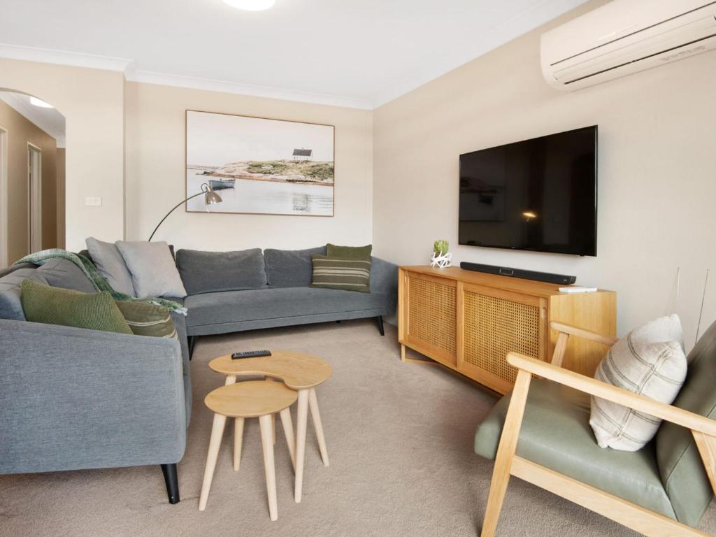 a living room with a couch and a tv at Avalanche 6 Stylish Modern Apartment in Central Location in Jindabyne