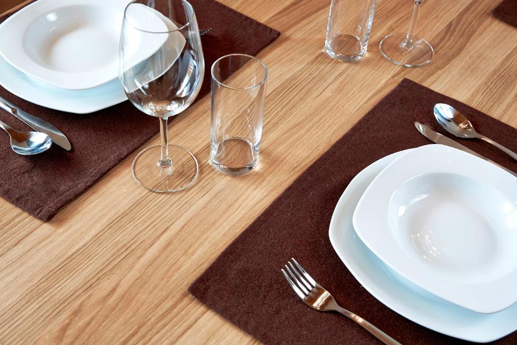 a wooden table topped with white plates and wine glasses at Kitz Mountain Living in Aurach bei Kitzbuhel