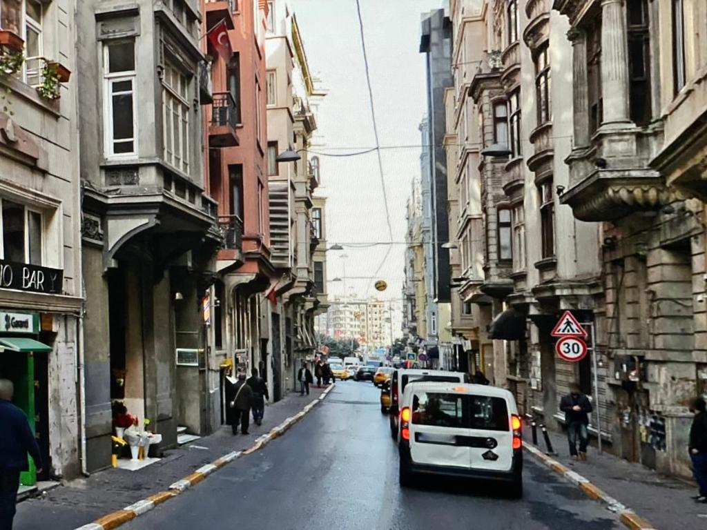 una macchina bianca che guida lungo una strada di città con edifici di Taksim Square-La Casa Home Concept a Istanbul