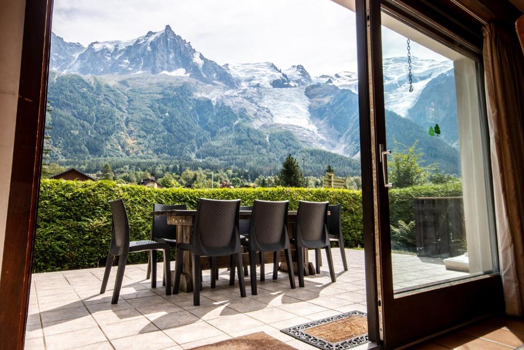 a table and chairs on a patio with a view of mountains at Chalet des Lacs - Chamonix in Chamonix