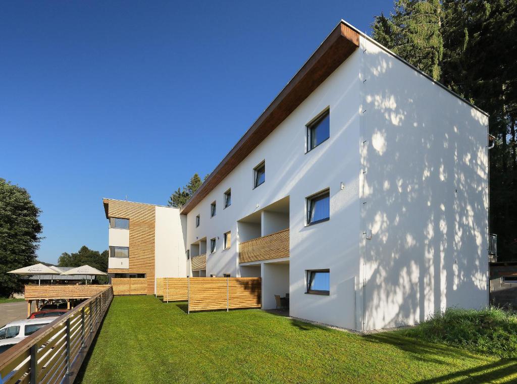 an exterior view of a white building with a yard at Apartmány Panelka Costa Plana Lipno in Černá v Pošumaví