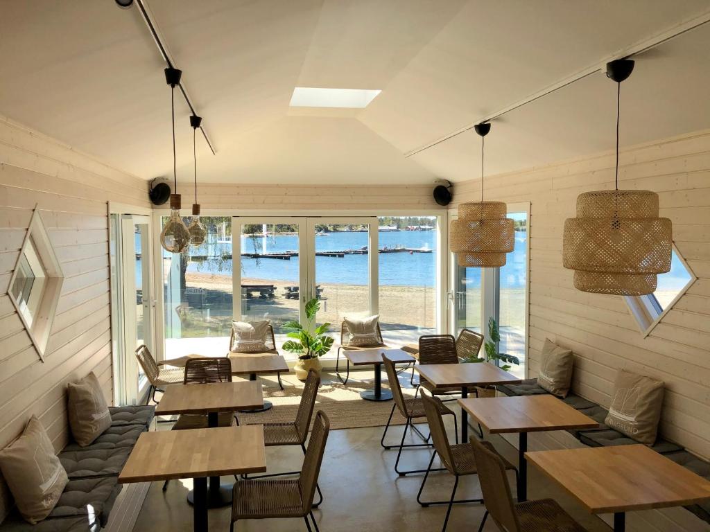 a restaurant with wooden tables and chairs and the ocean at Käringsund Resort in Eckerö