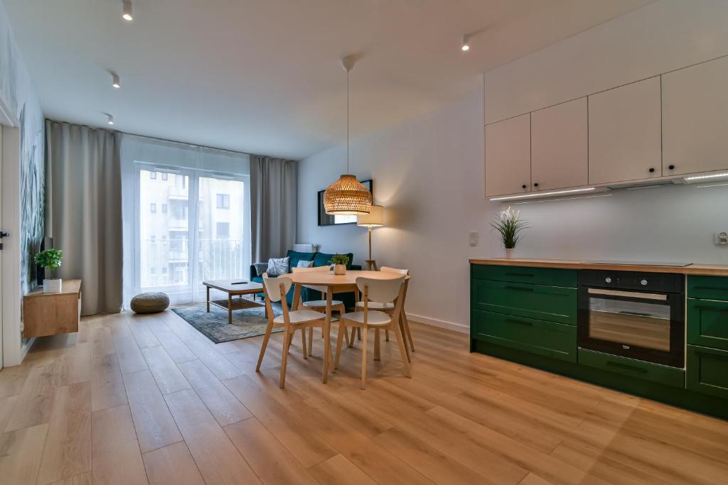 a kitchen with green cabinets and a table with chairs at LTC - Apartments Abrahama Śródmieście in Gdynia