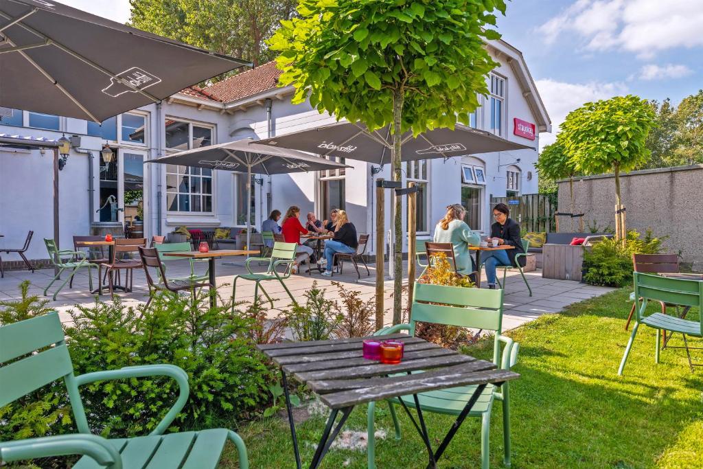 un patio con tavoli, sedie e ombrellone di Stayokay Hostel Haarlem a Haarlem