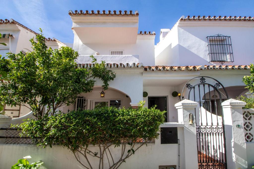 a white house with a gate and a tree at A cozy and elegant townhouse across the beach in Torre de Benagalbón