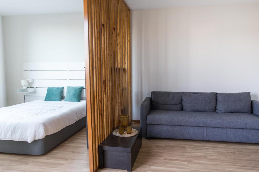um quarto com uma cama e um sofá em Estúdio Corujeira em Porto