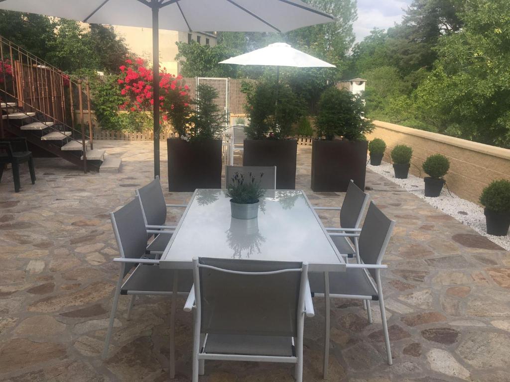 a table with chairs and an umbrella on a patio at Alojamientos El Horno in Montejo de la Sierra
