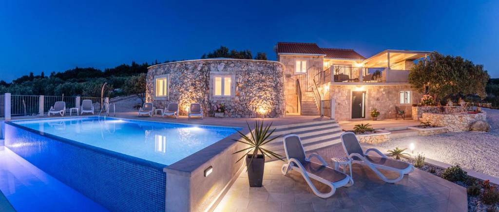 uma casa com uma piscina em frente a uma casa em Villa Lukrecija Stonehouse em Supetar