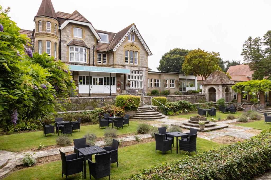 an exterior view of a mansion with tables and chairs at The Broadway Park Hotel in Sandown