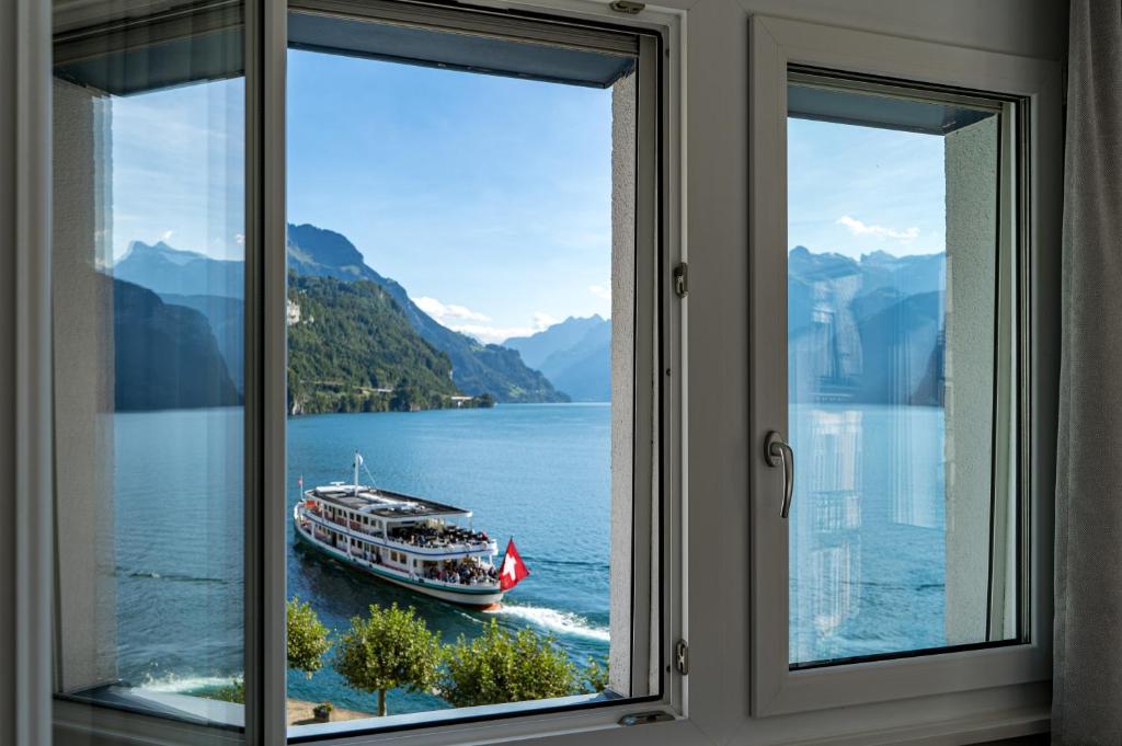 una ventana con vistas a un barco en el agua en Hotel Schmid & Alfa en Brunnen