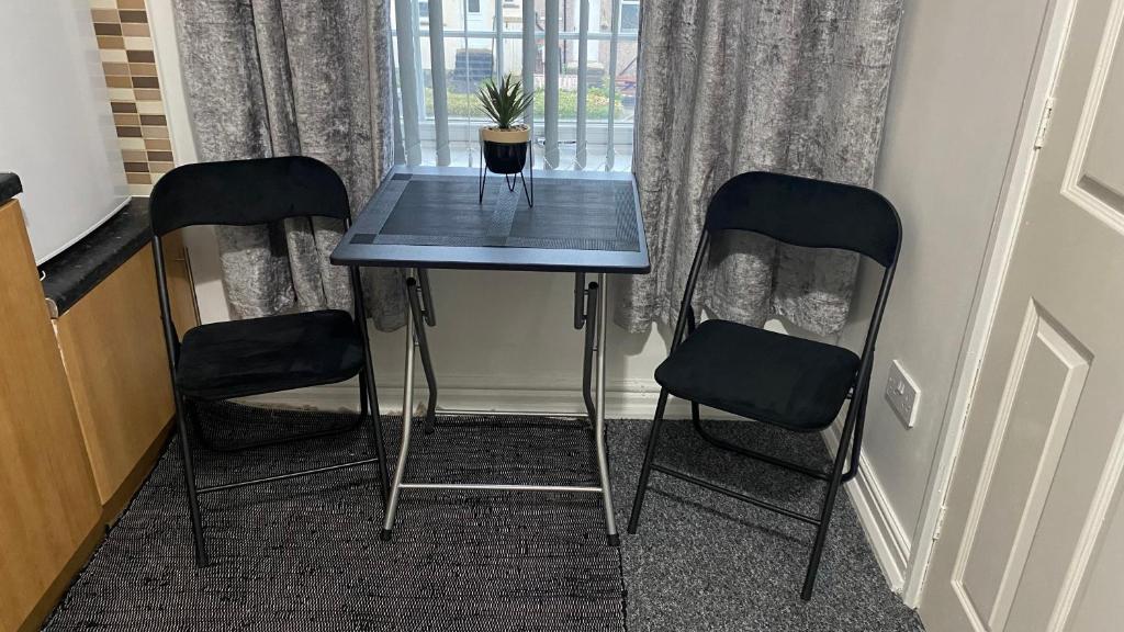 una mesa con dos sillas y una maceta en ella en bvapartments-Blackhouse en Huddersfield