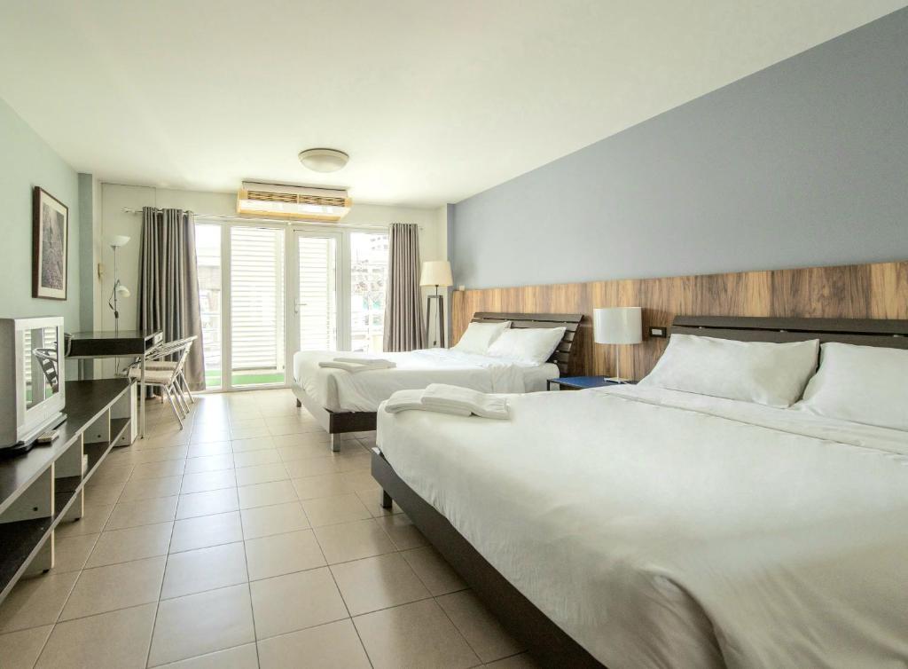ein Hotelzimmer mit zwei Betten und einem Fernseher in der Unterkunft The Studio at Sathorn Terrace in Bangkok