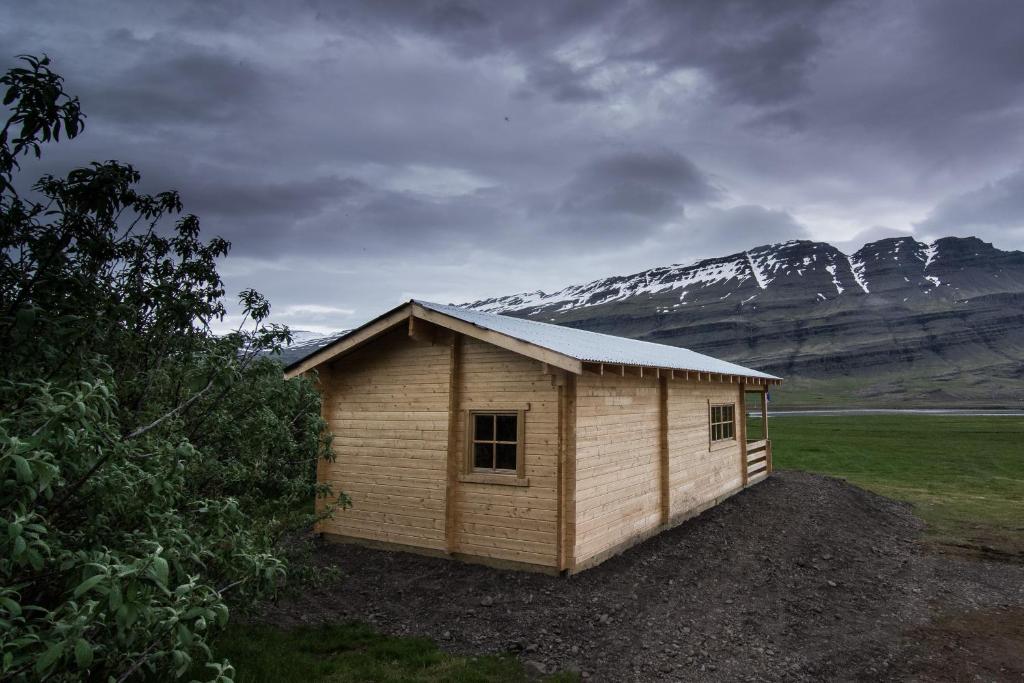 a small building in a field with mountains in the background at Bragdavellir Cottages in Djúpivogur
