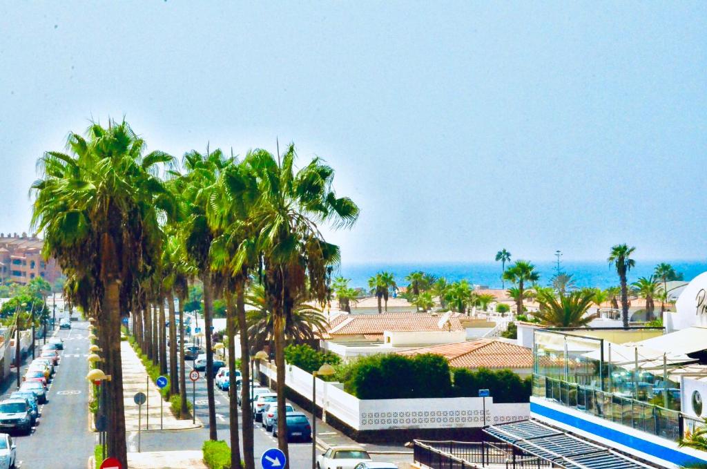eine Stadtstraße mit Palmen und dem Meer in der Unterkunft Shanti, La Casa Azul in Palm-mar