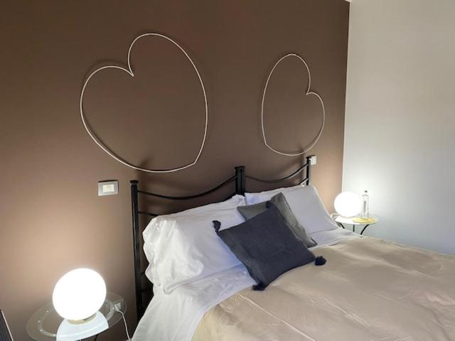 1 dormitorio con 1 cama con 2 corazones en la pared en Locanda Il Cortile, en Vignale