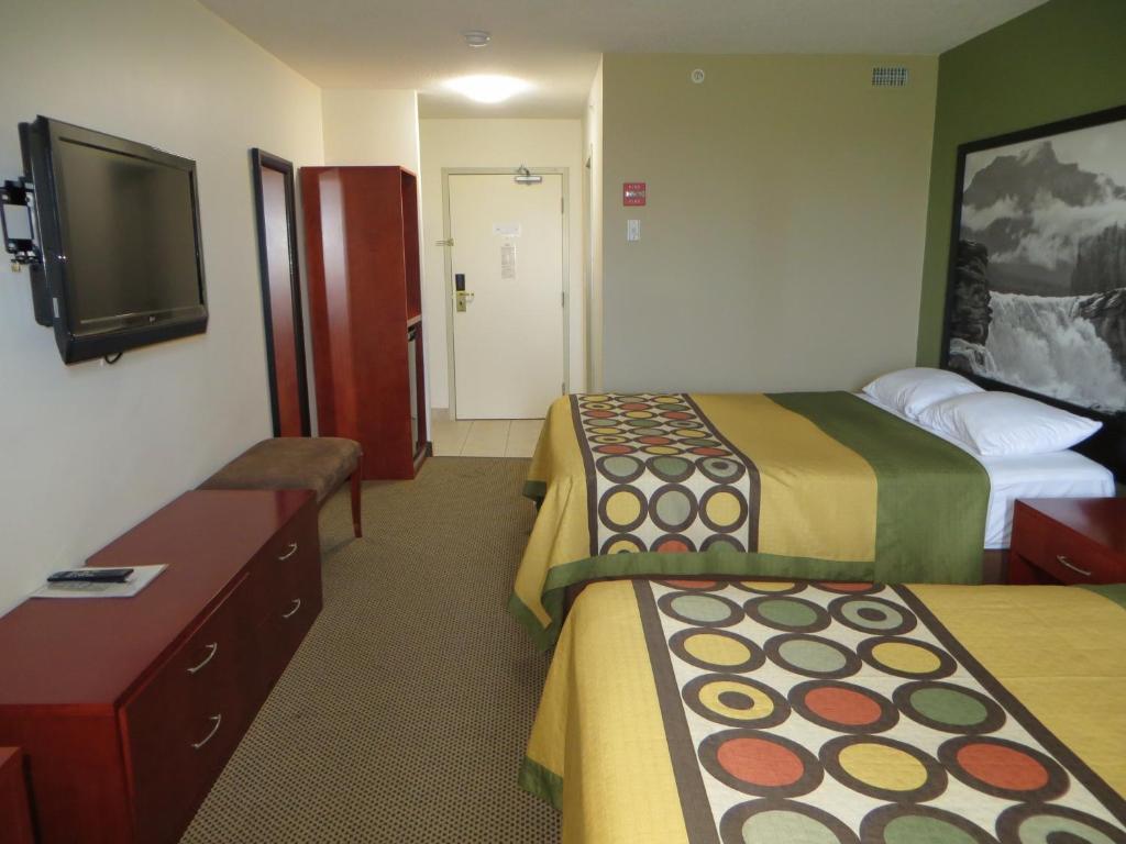 a hotel room with two beds and a flat screen tv at Super 8 by Wyndham Sherwood Park/Edmonton Area in Sherwood Park