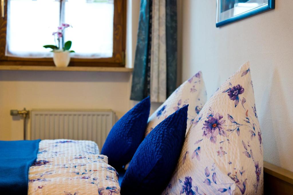 a bed with blue pillows on it with a window at Ferienwohnung AmmerZonas &amp; AmmerZone in Oberammergau