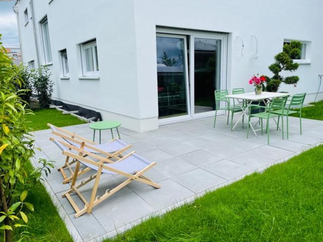 un patio con sillas, una mesa y una mesa con sillas en Ammersee Haus in Haus,wunderschöne Designerferienwohung mit Garten en Dießen am Ammersee