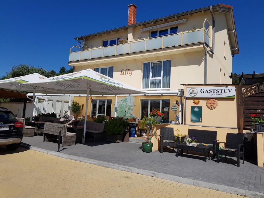 un bâtiment avec des tables et des parasols devant lui dans l'établissement Pension Lenz, à Sassnitz