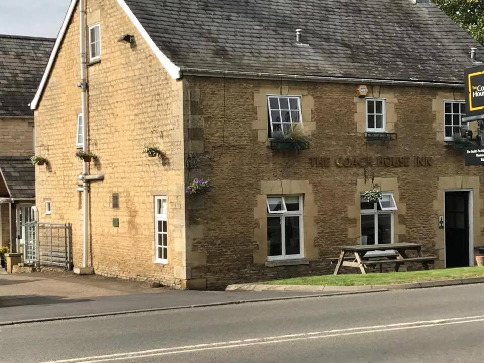 um edifício de tijolos com uma mesa de piquenique em frente em The Coach House Inn em Oakham