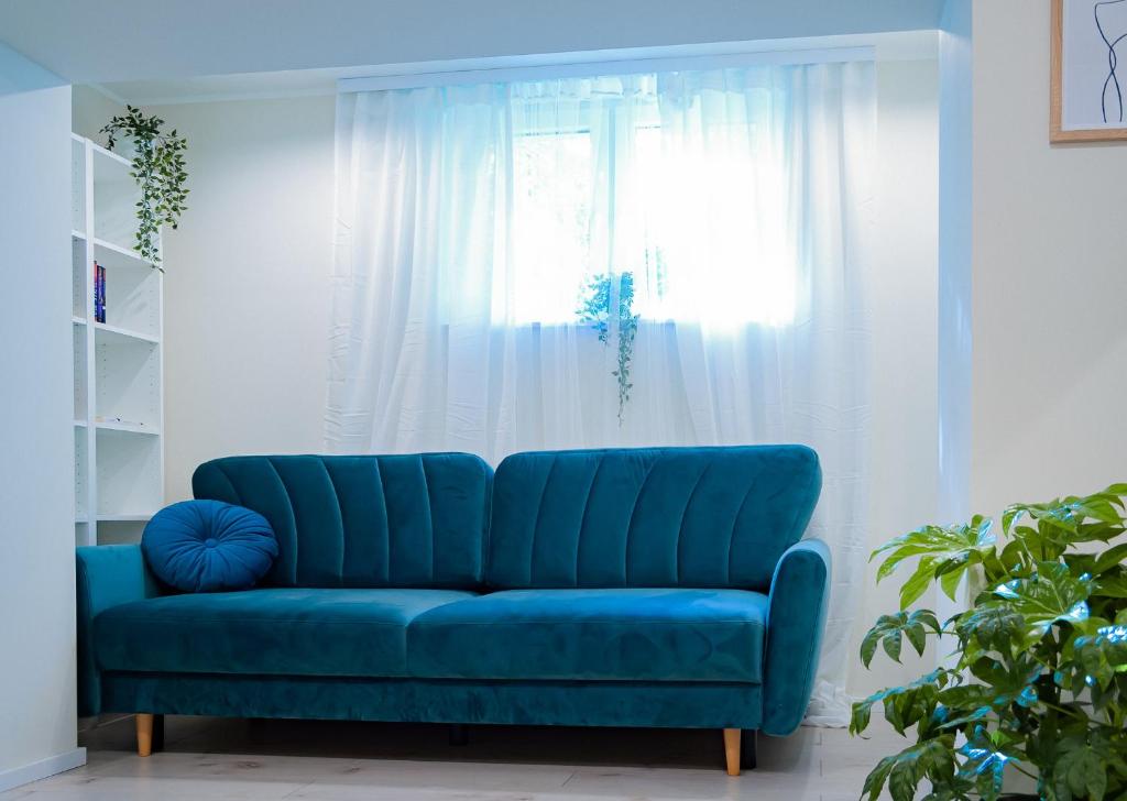 a blue couch in a living room with a window at APARTAMENT DLA 2 OSÓB - Fahrenheita 2 in Gdańsk