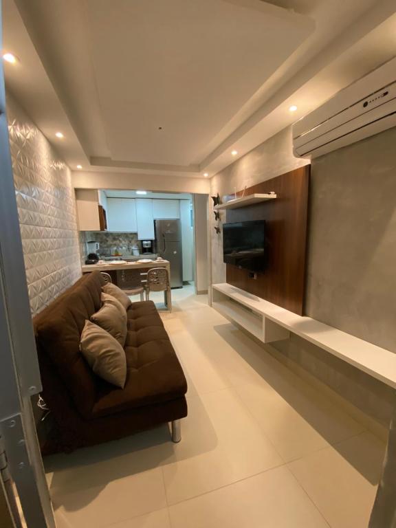 uma sala de estar com um sofá castanho e uma cozinha em Condomínio manguezal em Porto de Galinhas