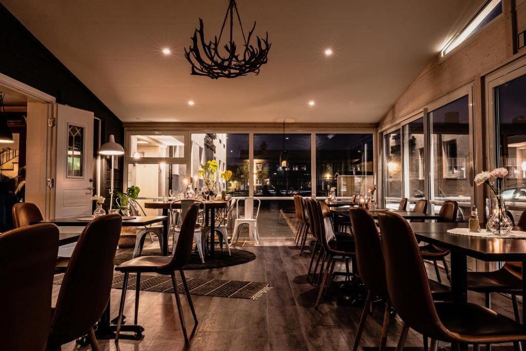 a restaurant with tables and chairs and a chandelier at Hotel Lapland River in Pajala