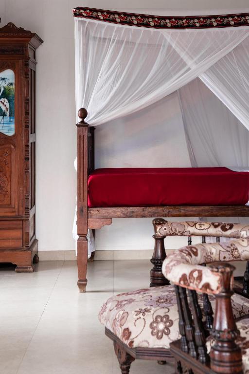 a bedroom with a bed with a canopy and a chair at Tembo House Hotel in Zanzibar City