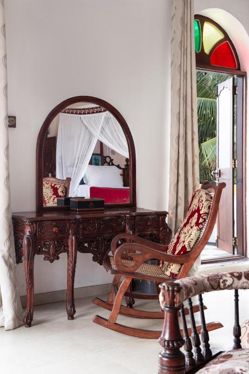 a desk with a mirror and a chair in a room at Tembo House Hotel in Zanzibar City