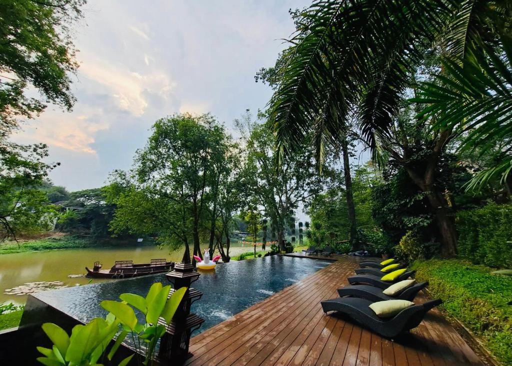 A riverside pool deck lined with loungers and tropical vegetation.