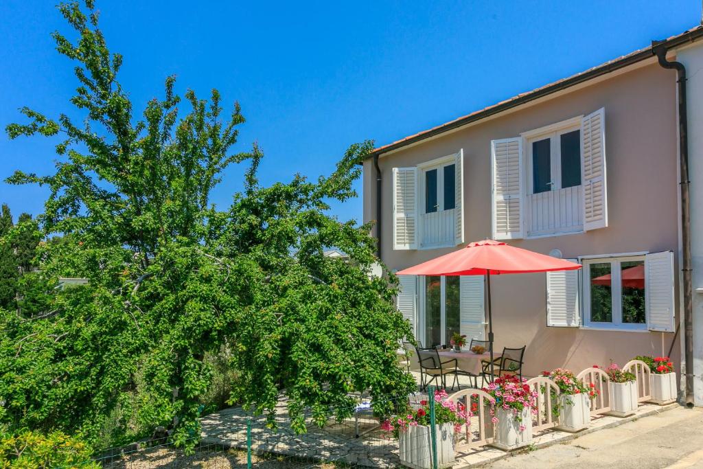 ein Haus mit einem Tisch mit einem Sonnenschirm und einem Baum in der Unterkunft House Milenka in Banjol