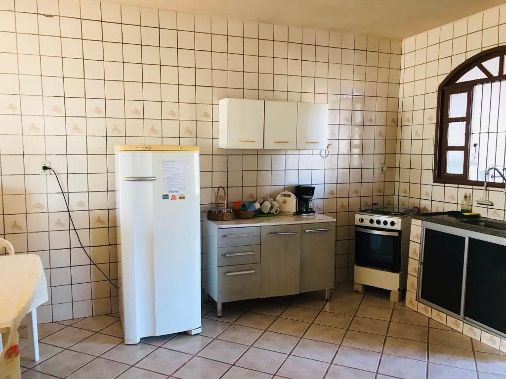 a kitchen with a white refrigerator and a stove at Jacaraipe ES -Lar de Praia casa temporada in Jacaraípe