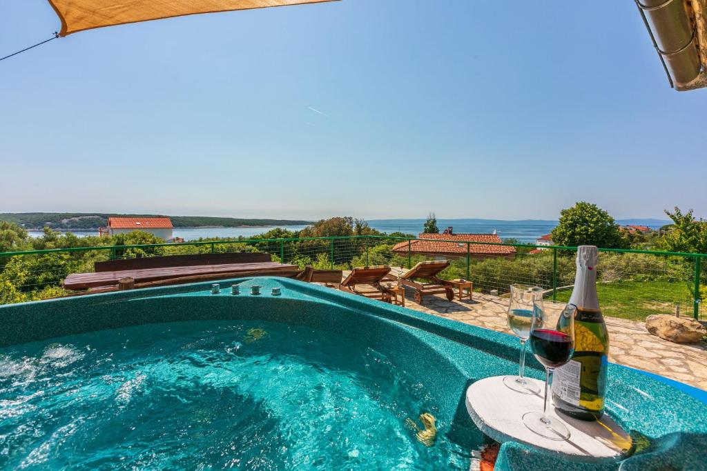 a pool with a bottle of wine and two glasses at Apartments Ljiljana in Supetarska Draga