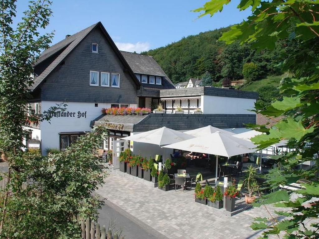 ein Gebäude mit Tischen und Sonnenschirmen davor in der Unterkunft Hotel Holländer Hof in Meschede