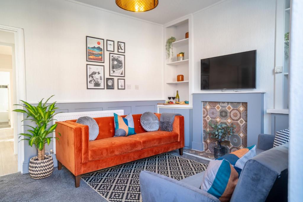ein Wohnzimmer mit einem orangenen Sofa und einem Kamin in der Unterkunft Saltbox Stays- Large 3 bed house!! 3 bathrooms, garden, fast wifi, sleeps 6 in Swadlincote