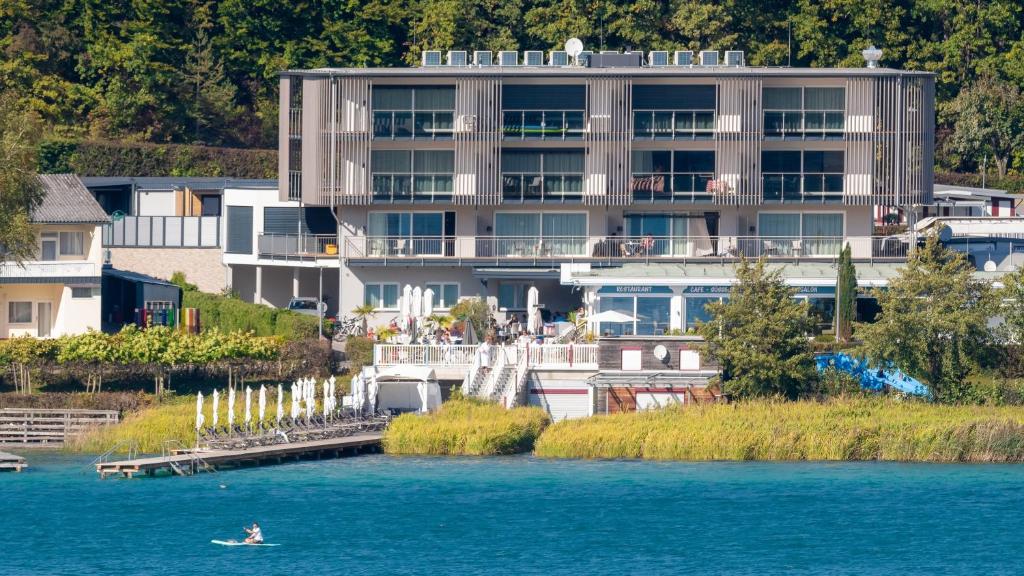 a person in a boat in the water in front of a building at Seewirt Apartments in Klopein am Klopeiner See