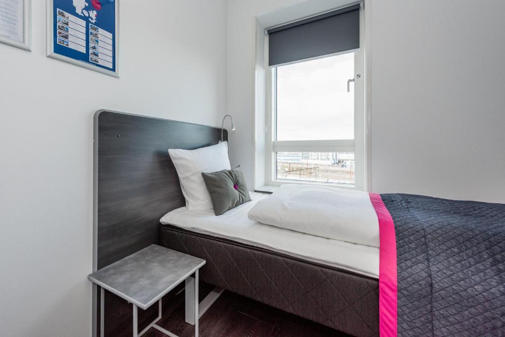 a small bedroom with a bed and a window at Cabinn Copenhagen in Copenhagen