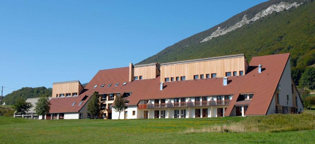 ein großes Gebäude mit einem Hügel im Hintergrund in der Unterkunft Le Piroulet in Vassieux-en-Vercors