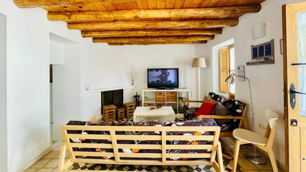 una sala de estar con paredes blancas y techo de madera. en La Cantarera en Linares de la Sierra