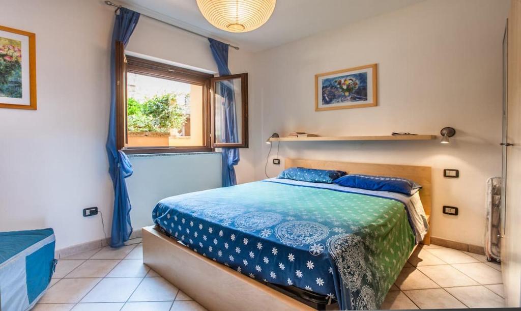 a bedroom with a bed with blue sheets and a window at Porto Alabe Sardegna.... a due passi dal mare in Tresnuraghes