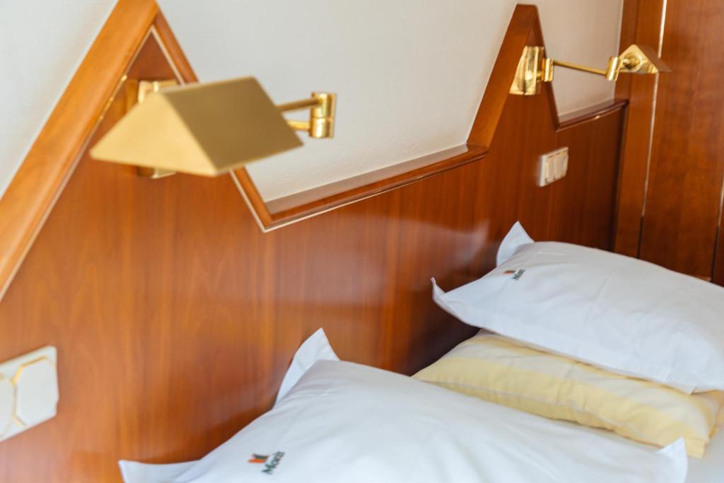 um quarto com uma cama com um candeeiro e almofadas em Hotel-Restaurant Moris em Walferdange