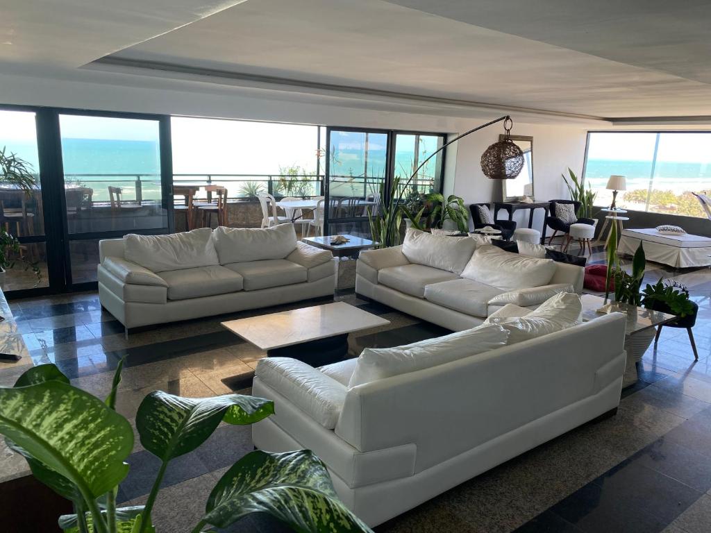 - un salon avec des canapés blancs, des tables et des fenêtres dans l'établissement Apartamento Oceano Praia Fortaleza, à Fortaleza