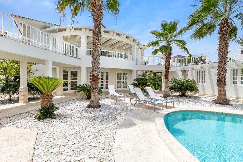 una gran casa blanca con palmeras y una piscina en Exclusive Punta Cana Resort and Club Pool Villas, en Punta Cana