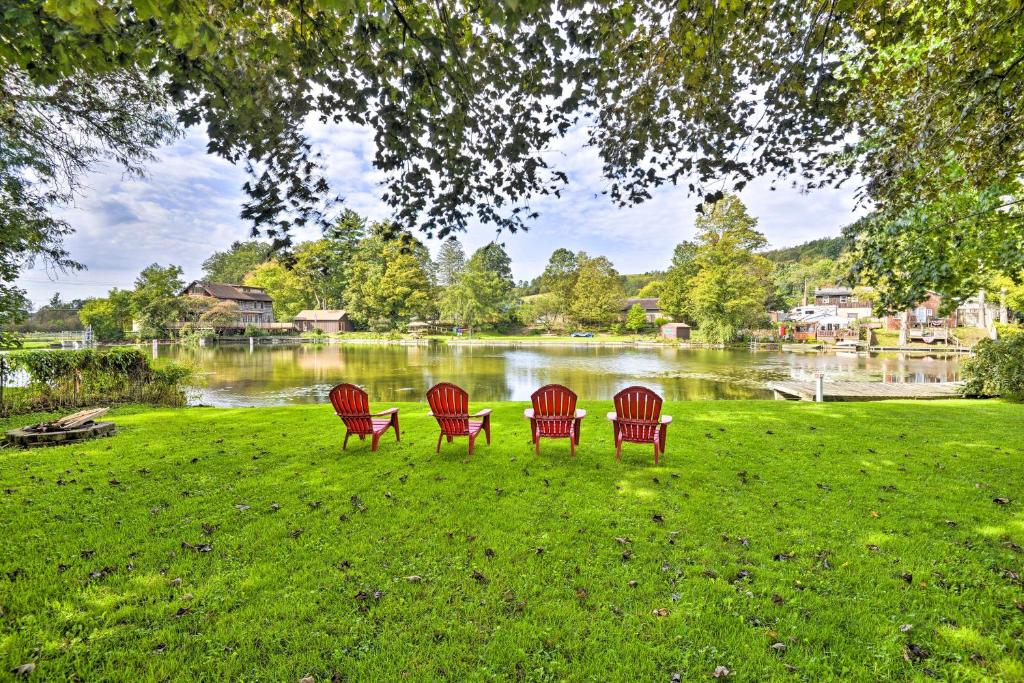 cuatro sillas rojas sentadas en el césped cerca de un lago en Quiet New York Retreat Less Than 7 Miles to Skiing! en Homer