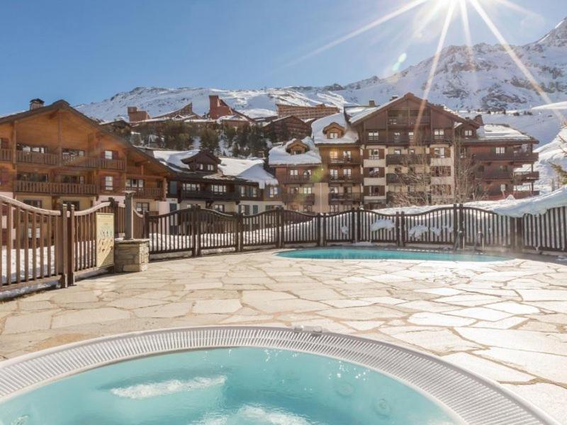 a swimming pool in front of a building with snow covered mountains at Apt Résidence 5* Arc 1950 3 pièces 6 couchages in Arc 1950