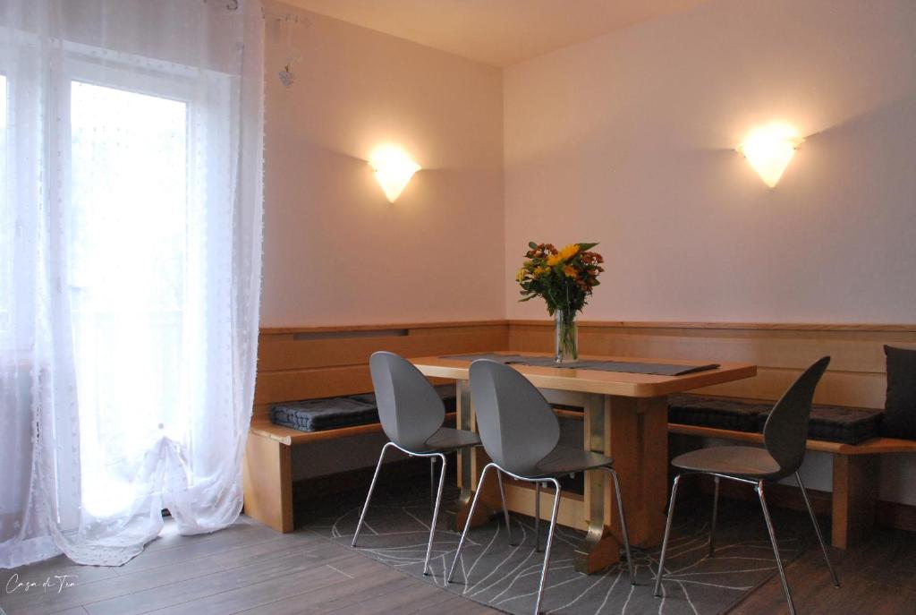 una habitación con una mesa con sillas y un jarrón de flores en Casa di Tea, en Pieve di Cadore